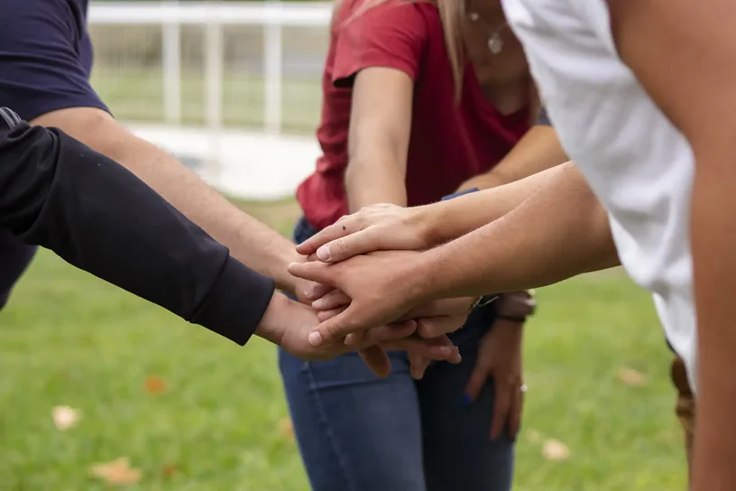Equipo uniendo las manos en una dinámica de colaboración