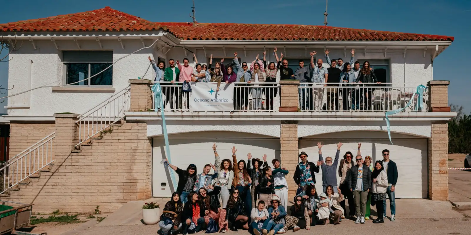 Grupo de participantes de un evento de empresa de Océano Atlántico celebrando en el exterior de una casa rural
